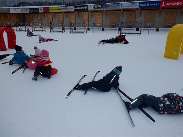 Eine Gruppe von Menschen, die mit Skiern auf dem Schnee sitzen